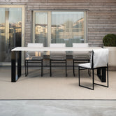 Isa outdoor chairs with black frames and white cushions paired with the Diana outdoor dining table by by Crea, styled on a modern balcony with wood paneling and city views.