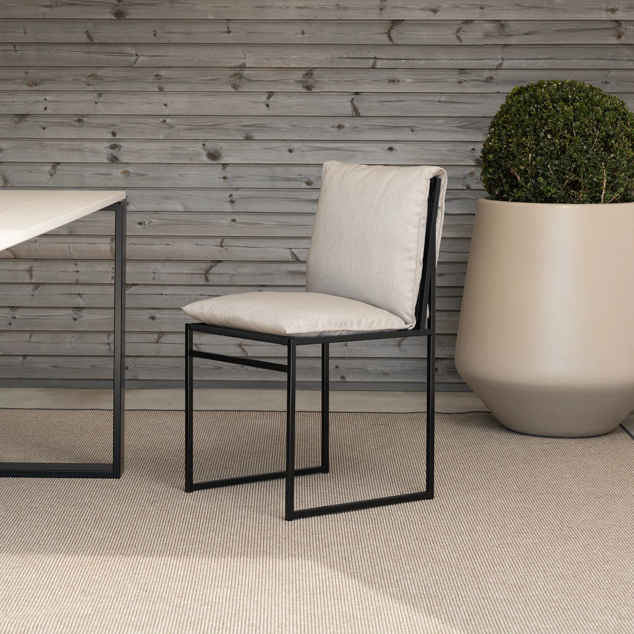 Isa outdoor chair in black frame with fossil acrylic, featuring minimalist Scandinavian design for timeless elegance.