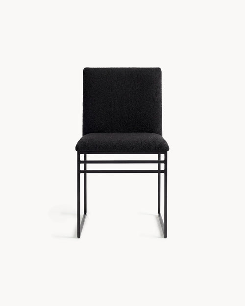 Dining chair Isabell in black, featuring a steel frame and a black bouclé cushion, ideal for dining spaces.