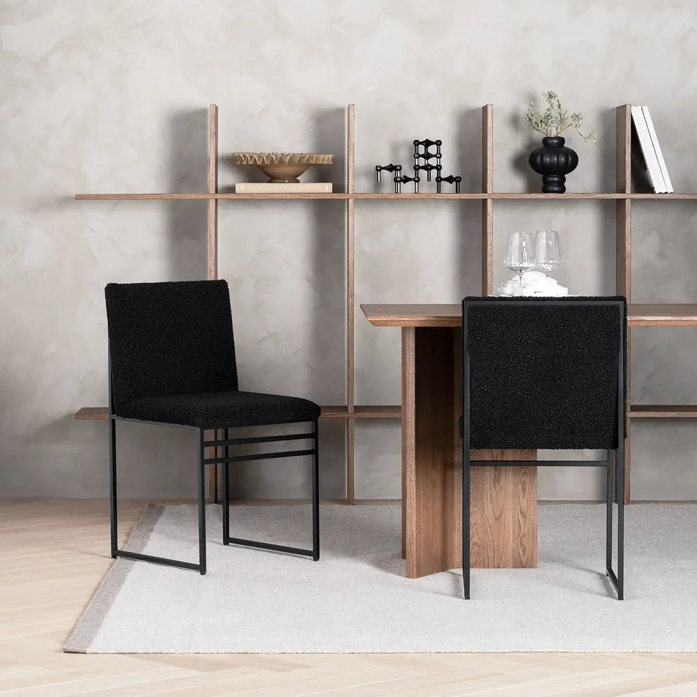 Dining chair Isabell with black bouclé cushion and frame in modern dining room setting.