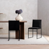 Dining chair Isabell with black frame and jade black velvet cushion placed at a modern dining table.