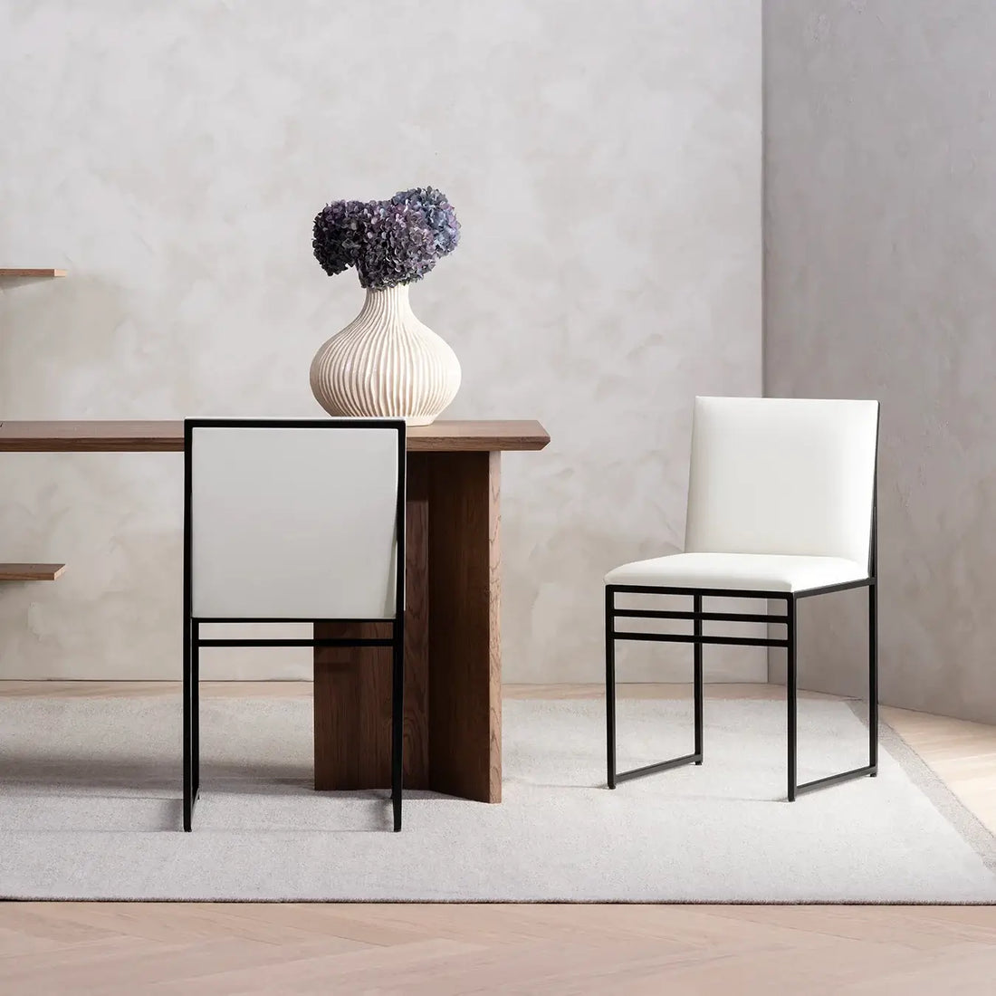 Dining chair Isabell with black frame and ivory leather cushion in a modern dining setting.