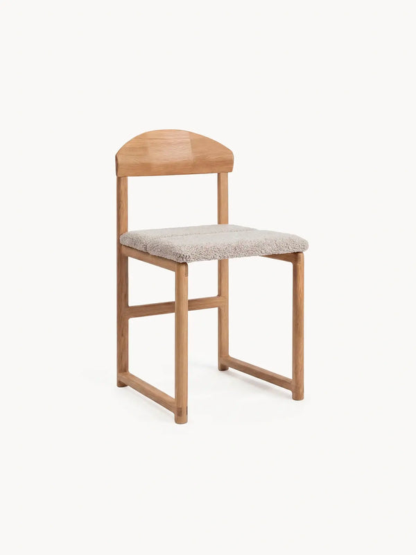 Wooden chair with a boucle cushion on a white background