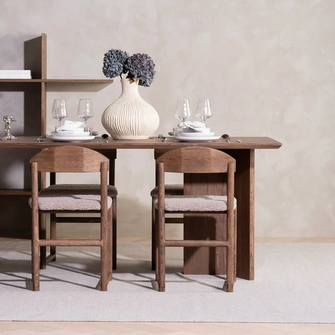 Dining chair Karin in dark oak wood frame with greige bouclé cushion at a stylish dining table.