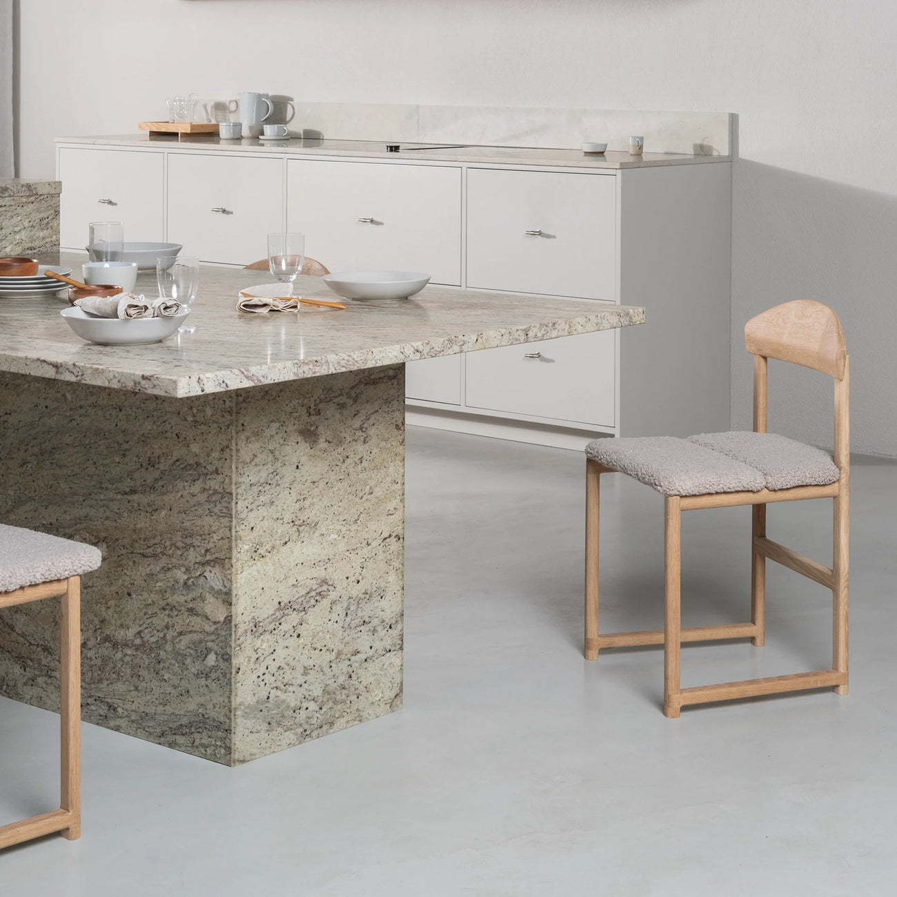 Karin dining chair in oak with greige bouclé at a modern table setting, showcasing soft neutral style and solid craftsmanship.