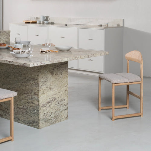 Karin dining chair in oak with greige bouclé at a modern table setting, showcasing soft neutral style and solid craftsmanship.