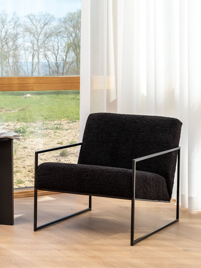 Armchair Kent – stylish black armchair with bouclé cushion and black frame in a minimalist Scandinavian interior design.