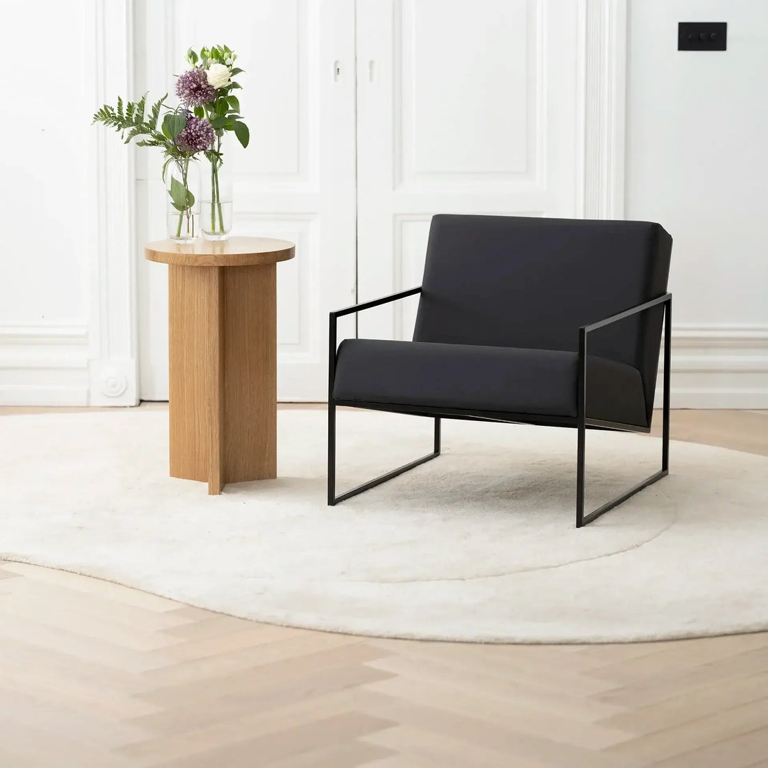 Armchair Kent in black frame with jade black leather cushion, modern Scandinavian style in a stylish interior.
