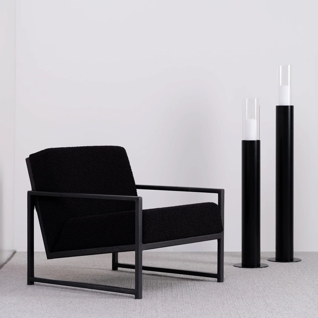 Minimalist black oak armchair with black bouclé seat, featuring modern design and relaxed support.