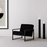 Armchair Einar in black oak frame and black bouclé cushion, minimalist design with modern styling.