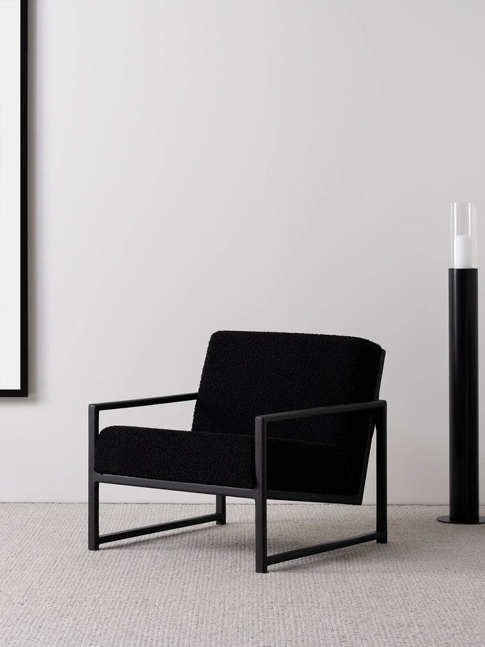 Armchair Einar in black oak frame and black bouclé cushion, minimalist design with modern styling.