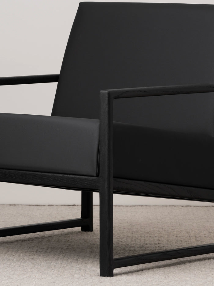 Armchair Einar in jade black leather cushion with black oak frame, featuring a sleek Scandinavian design.
