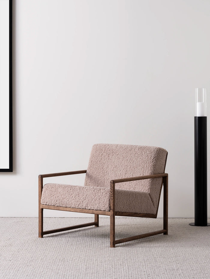 Armchair Einar with dark oak frame and greige bouclé cushion in a stylish interior setting.