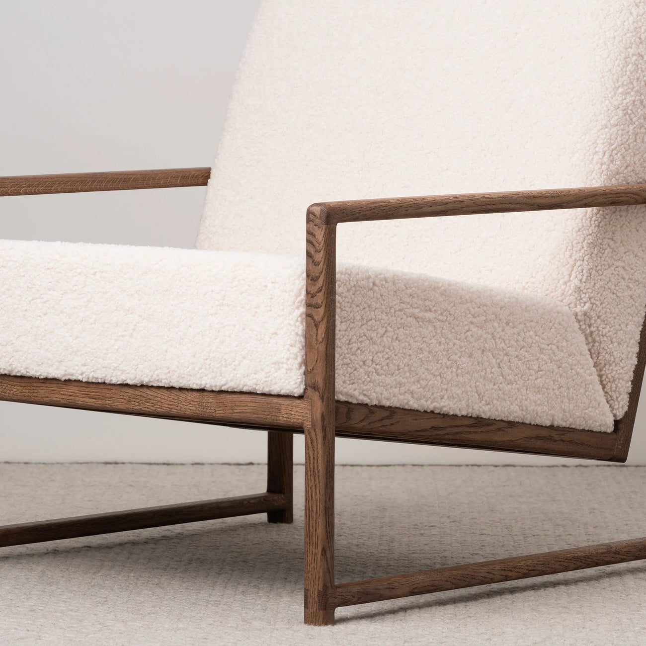 Dark oak armchair with soft ivory bouclé upholstery, adding warmth and Scandinavian comfort to any cozy space.