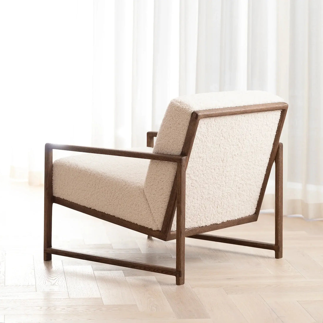 Armchair Einar with dark oak frame and ivory bouclé cushion, designed for Scandinavian comfort in cozy spaces.