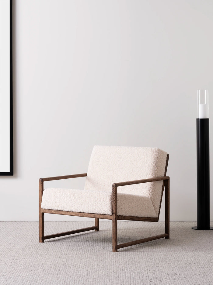 Armchair Einar featuring dark oak frame and ivory bouclé cushion, perfect for Scandinavian-style living spaces.
