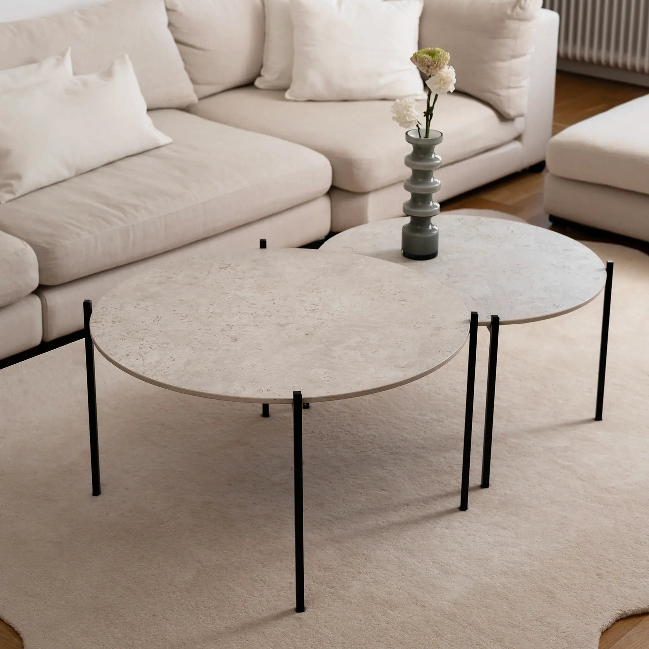 Leo Coffee Table 2-set by by Crea in Sabbia Dekton and black steel, shown in a Scandinavian living room with a cream corner sofa and ceramic vase. Handmade modern coffee tables for stylish interiors.