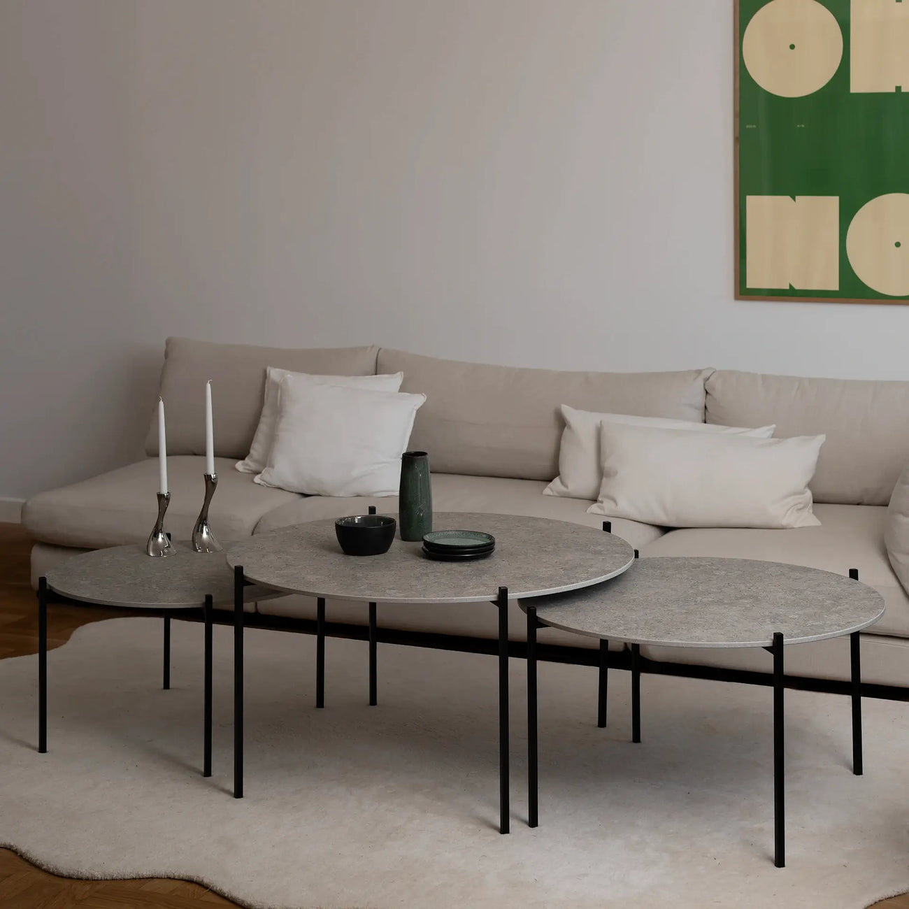 Leo Coffee Table 3-set by by Crea in Grigio Dekton with black steel frame, styled with green ceramics and silver candle holders in a Scandinavian living room with modern wall art and a beige sectional. Handmade designer furniture for contemporary interiors.