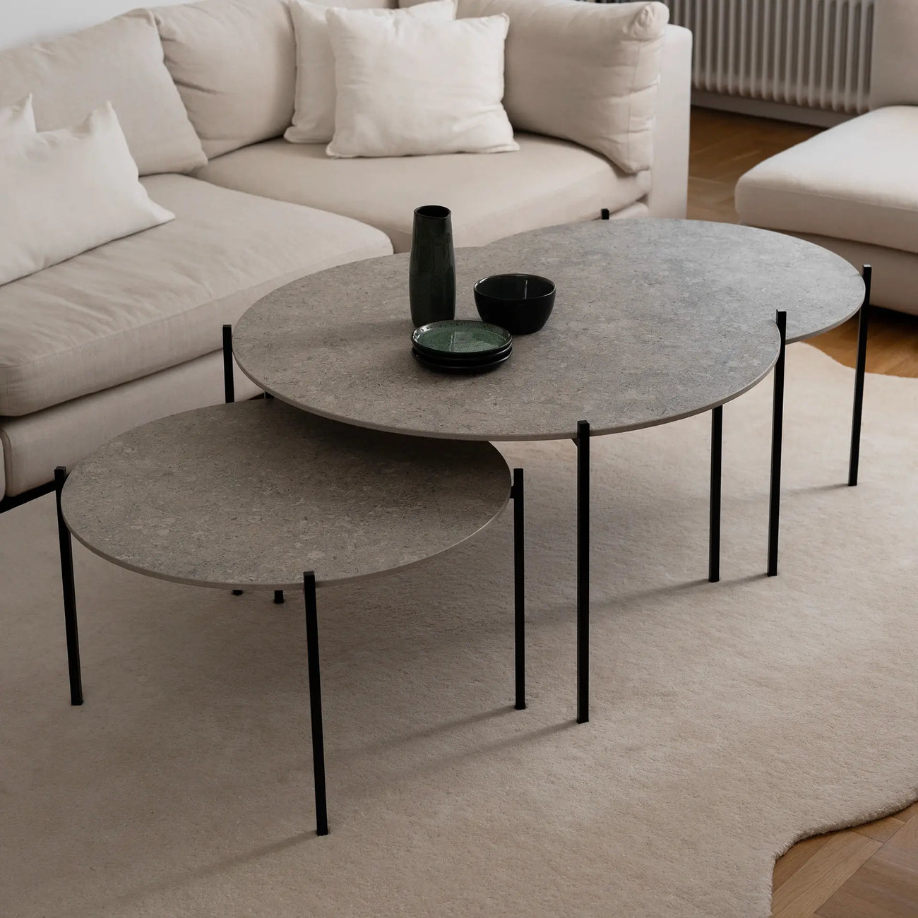 Leo Coffee Table 3-set by by Crea with Grigio Dekton tops and black steel frames, styled in a Scandinavian living room with a beige sectional sofa and soft wool rug. Handmade designer coffee tables for modern interiors.