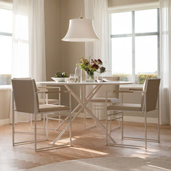 Front view of the Luna round dining table in white frame with matching Sella armchairs in beige vegan leather, styled in a light-filled Scandinavian dining room.