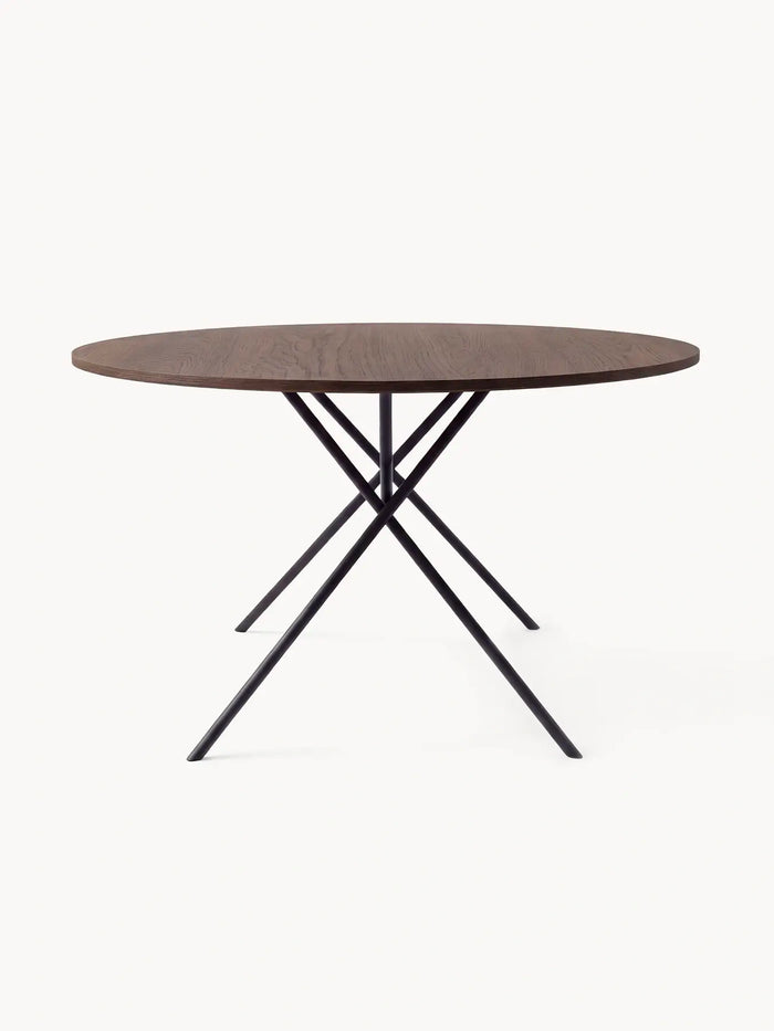 Round Dining Table Luna in dark stained oak, seen at eye level showing the crossed black steel legs