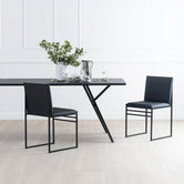 Melker Dining table in black oak with sleek black chairs and floral centerpiece, ideal for modern dining spaces.
