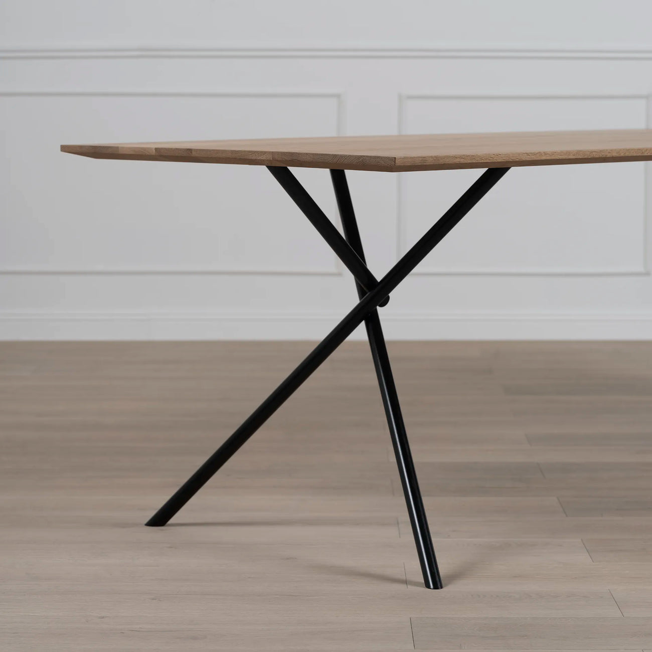 Melker dining table in black and natural oak with modern design and unique x-shaped legs.