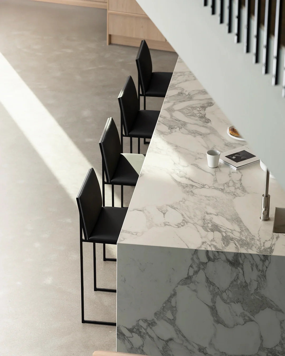 Set of four Philip bar stools in black frame and black vegan leather, styled at a modern marble kitchen island by by Crea.