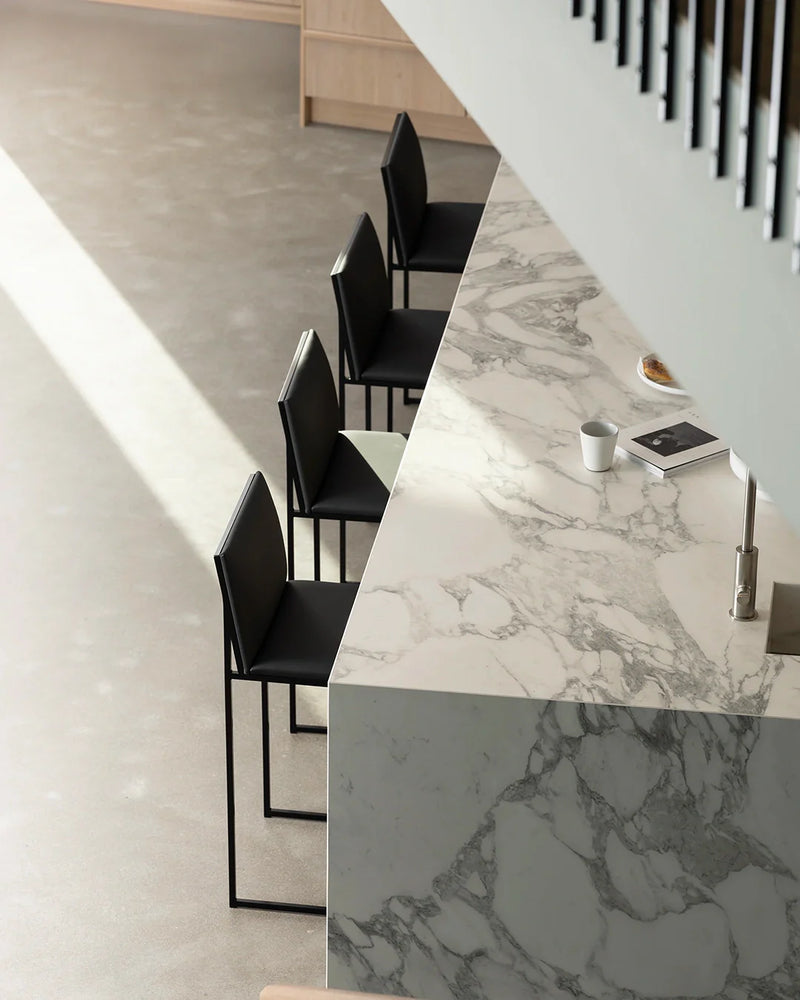 Set of four Philip bar stools in black frame and black vegan leather, styled at a modern marble kitchen island by by Crea.