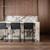 Philip black bar stools with high backs at a modern kitchen island with marble countertop.