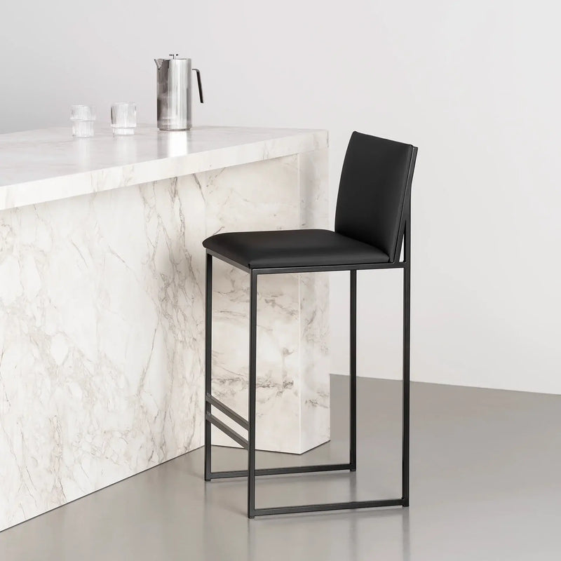 Bar Stool Philip with black frame and jade black leather cushion at a marble kitchen island.