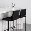 Philip bar stools with black velvet seats and sleek black frames at a marble countertop, showcasing modern interior design.