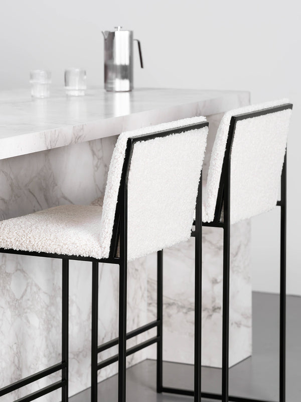 Bar Stool Philip with black frame and ivory bouclé cushion at a marble kitchen island.