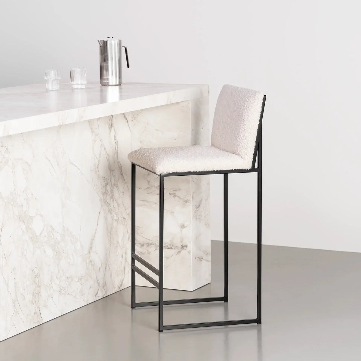 Bar Stool Philip with black frame and ivory bouclé cushion at a kitchen island.