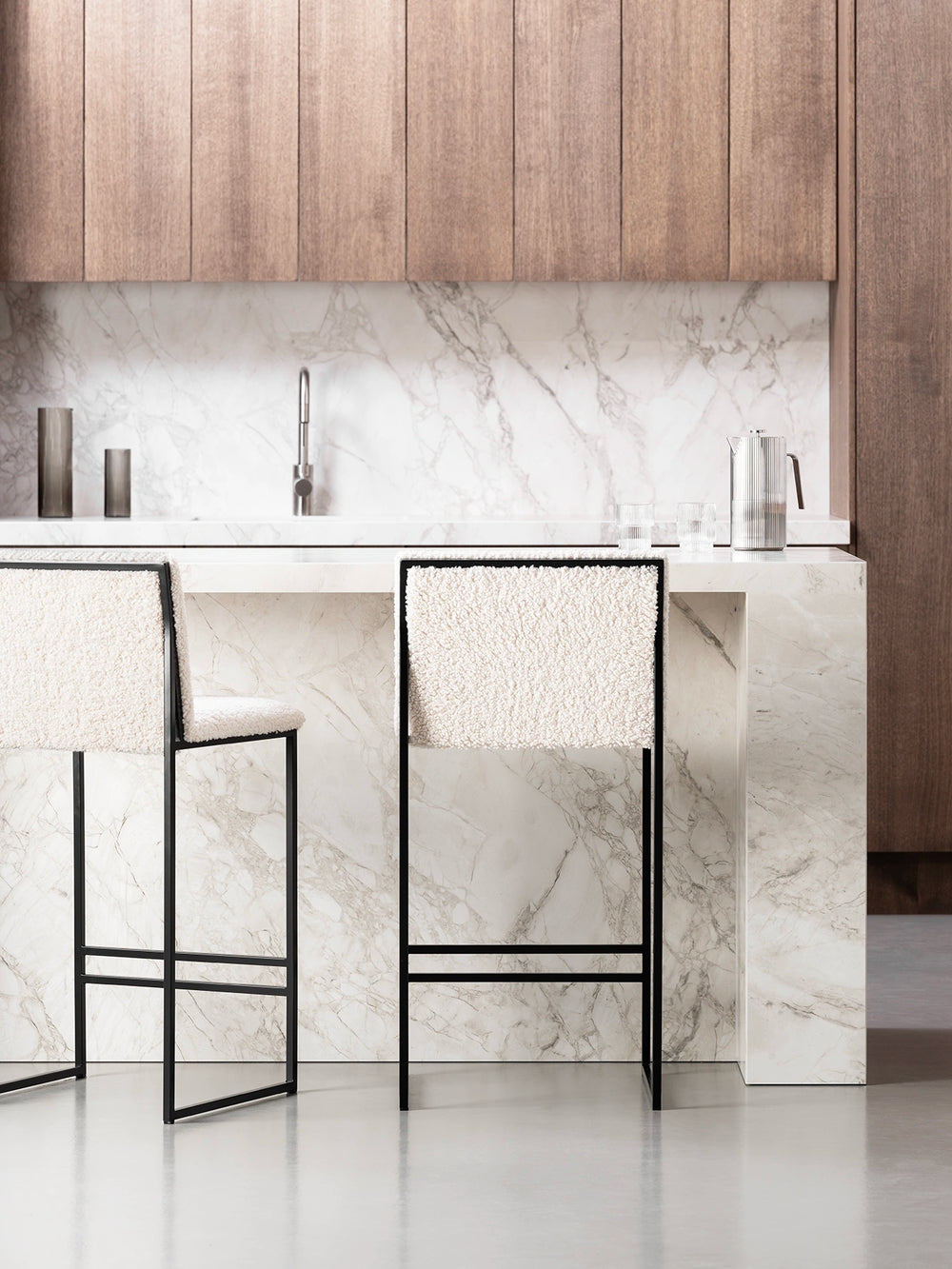 Bar Stool Philip with black frame and ivory bouclé cushion at a modern kitchen island.
