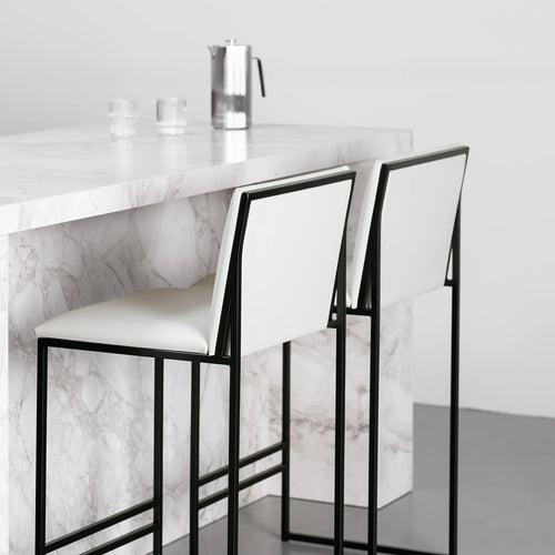Philip Bar stool with black frame and ivory leather seat, stylishly placed at a marble counter in a modern interior.