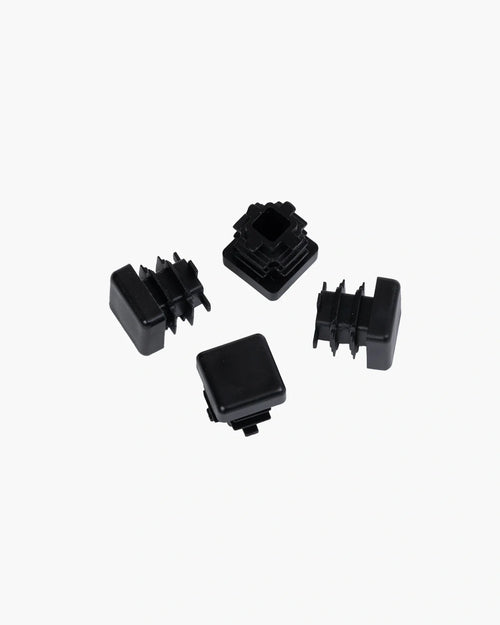 Set of four stylish black plastic feet for furniture protection and floor safety.