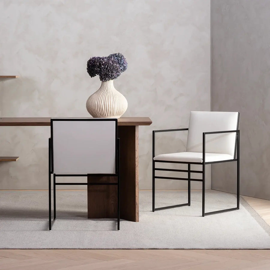 Dining chair Sella with black frame and ivory leather armrest in a modern dining setting.