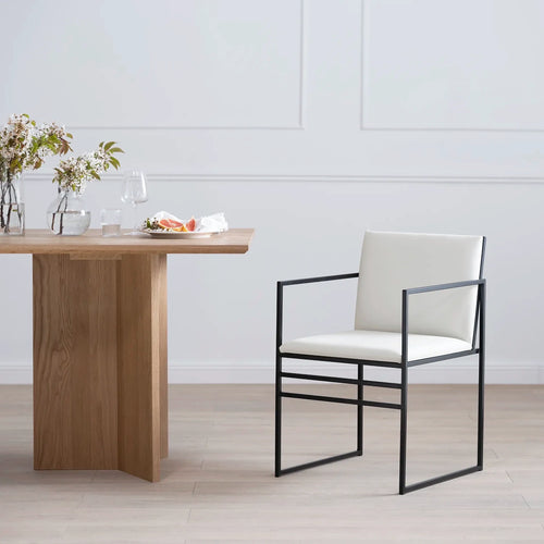 Sella dining chair in black metal frame with ivory leather seat, showcasing minimalistic design in a stylish dining setting.