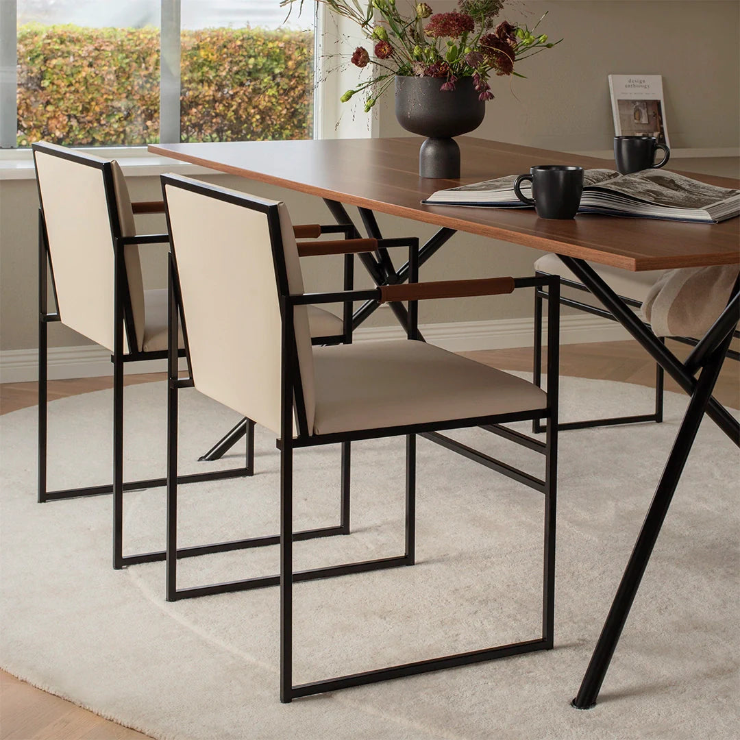 Sella dining chair with black frame and latte leather, featuring chocolate armrests in a modern dining setting.