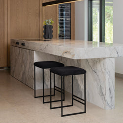 Svea bar stools with black bouclé seats in modern kitchen setting with marble countertop and wood cabinets.