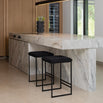 Svea bar stools with black bouclé seats in modern kitchen setting with marble countertop and wood cabinets.