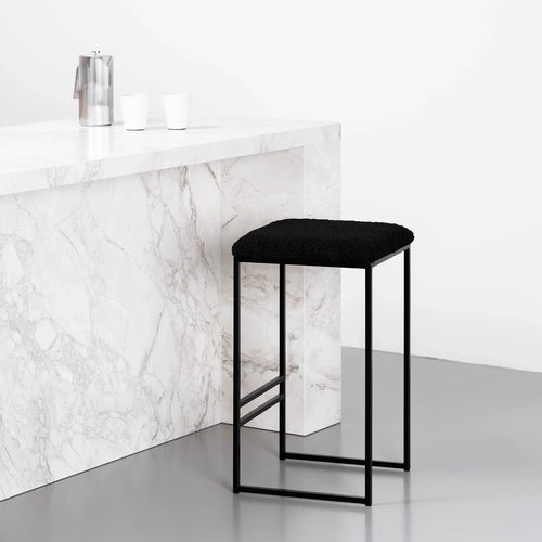 Svea Bar stool in black with bouclé seat, featured against a marble countertop, perfect for stylish high seating.
