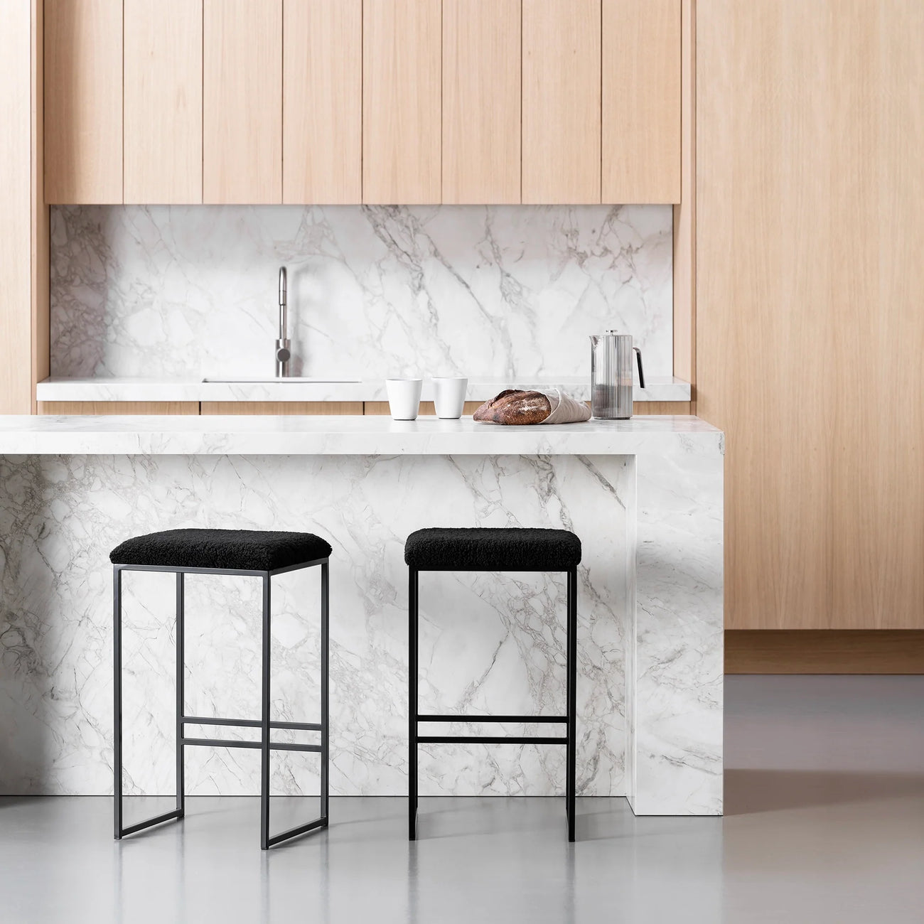 Svea bar stools with black bouclé seats and black frames in a stylish kitchen setting.