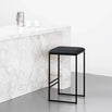 Svea bar stool in black leather with a sleek metal frame, set against a modern marble countertop.