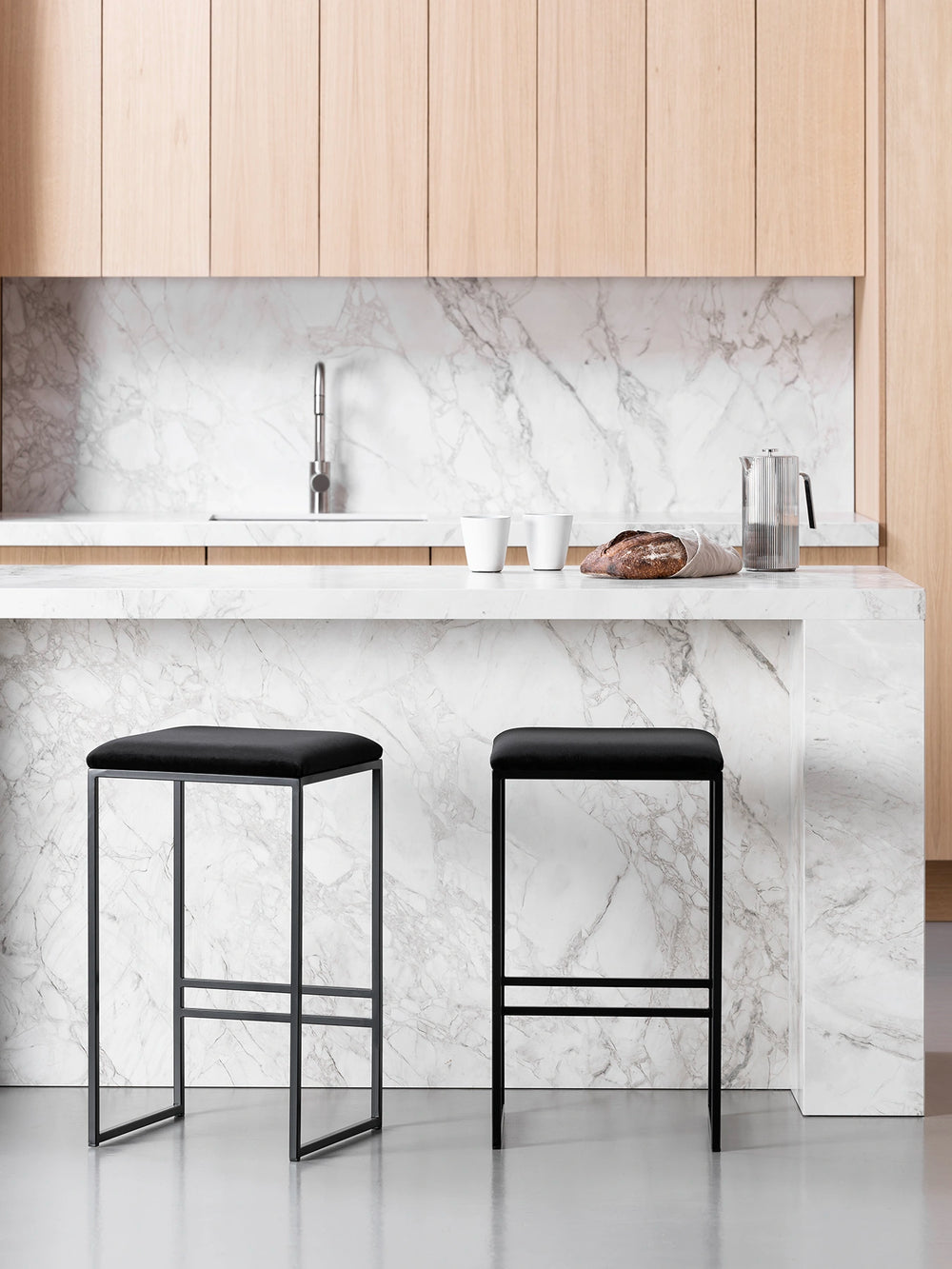 Bar Stool Svea in black velvet placed at a modern kitchen island with a marble countertop.