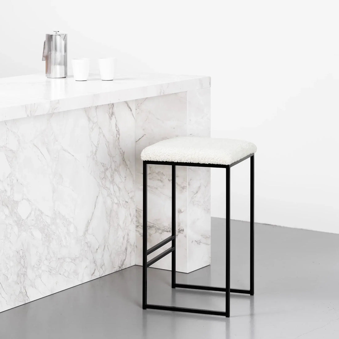 Bar Stool Svea in black with ivory bouclé, placed by a marble countertop, highlighting the stylish Bar Stool design.