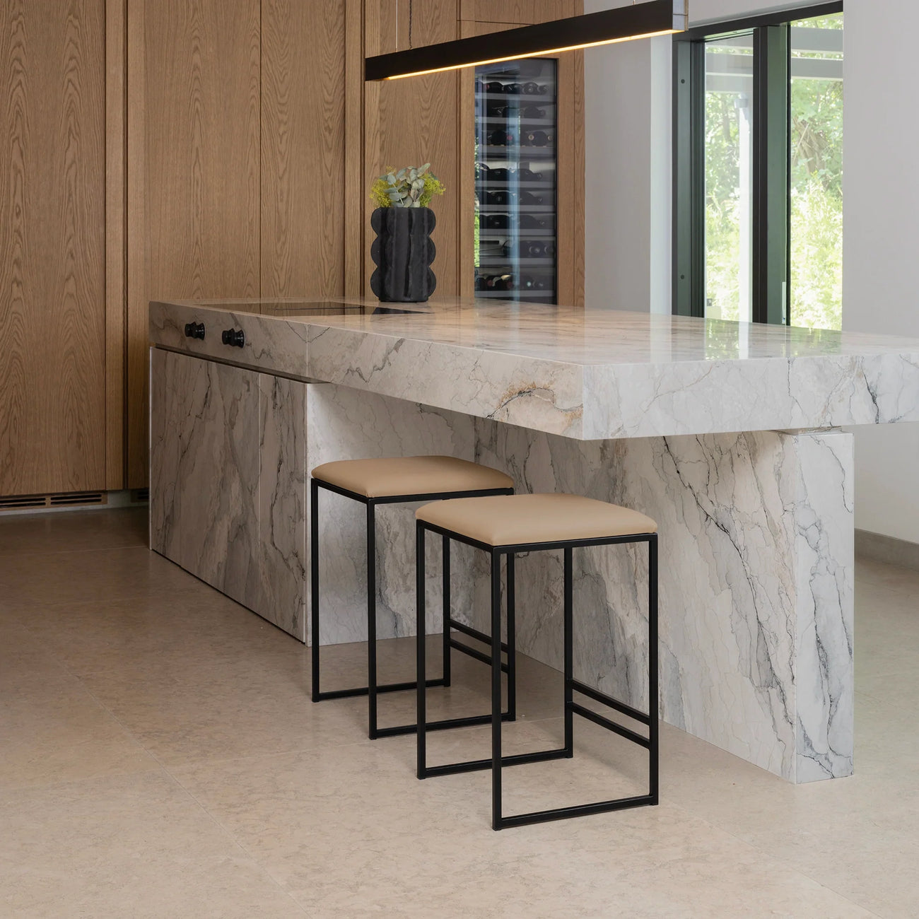 Svea bar stools with black frame and latte leather seats at a marble kitchen island.