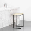 Svea black bar stool with sand leather seat against a marble countertop, showcasing a modern and minimalistic design.