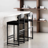 Sleek black oak bar stools with black bouclé seats at a modern kitchen counter.